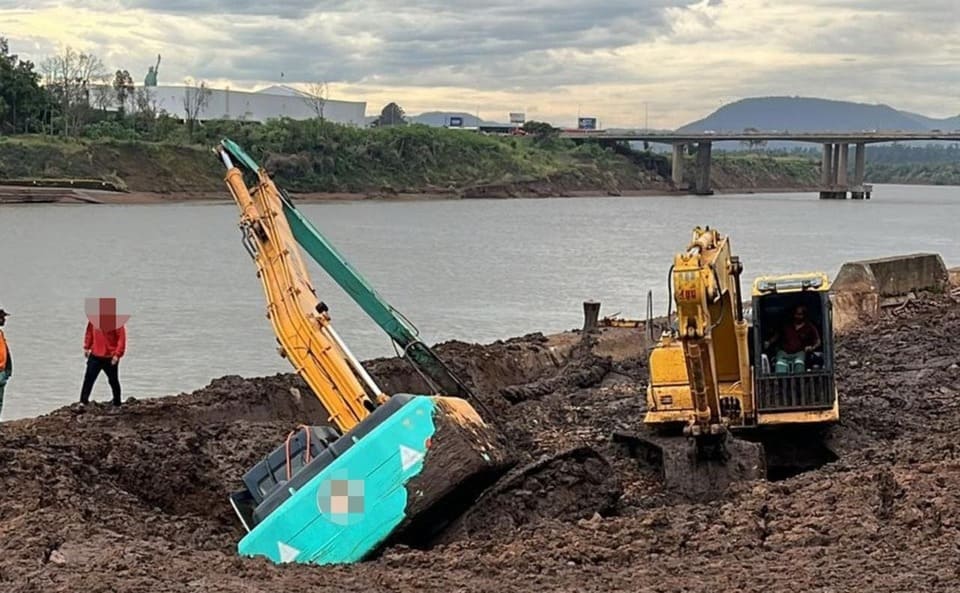 Empresa é acusada de jogar lama no Taquari, mas salvava colega preso em escavadeira.