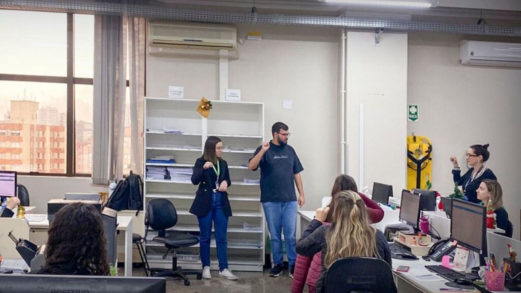 Profissional do Tacchini com deficiência auditiva dá aula de Libras a colegas.